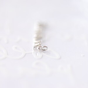 May include: A silver chain with a small loop at the end. The chain is made of small, square links.