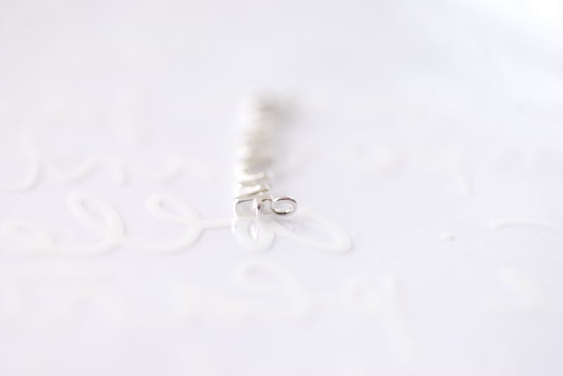 May include: A silver chain with a small loop at the end. The chain is made of small, square links.