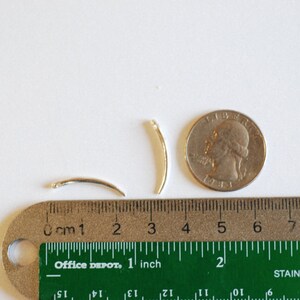 Op de afbeelding: Twee zilverkleurige metalen draadringen, elk met een diameter van ongeveer 2,5 cm, worden getoond naast een liniaal en een Amerikaanse kwart. De liniaal is gemarkeerd in zowel inches als centimeters.