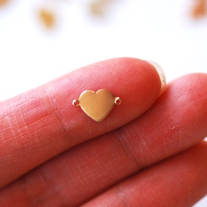May include: A gold-colored heart-shaped charm with two jump rings for attaching to jewelry.