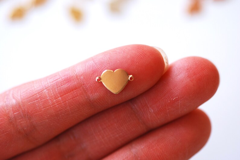 May include: A gold-colored heart-shaped charm with two jump rings for attaching to jewelry.