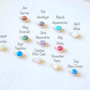 May include: Twelve small, round, gemstone charms with gold connectors. Each charm represents a different month of the year and features a different birthstone. The charms are arranged in a row, starting with January and ending with December.
