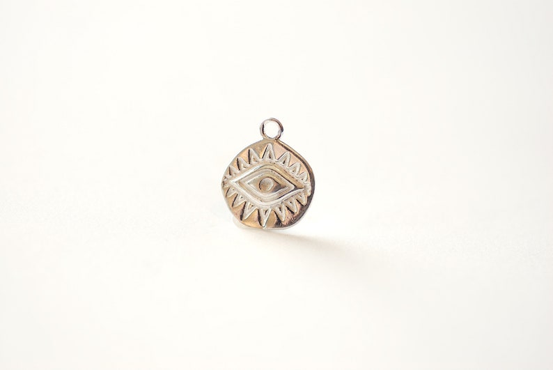 Puede incluir: Encanto de plata con un dise&ntilde;o de ojo malvado detallado. El ojo est&aacute; rodeado por un patr&oacute;n de estrella.