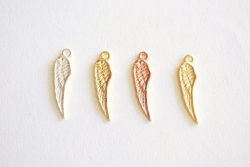 May include: Four angel wing charms in different metal finishes: silver, gold, rose gold, and copper. Each charm features a detailed wing design.