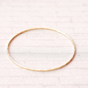 May include: A simple gold bangle bracelet with a hammered texture.