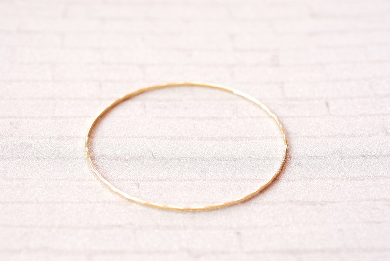 May include: A simple gold bangle bracelet with a hammered texture.