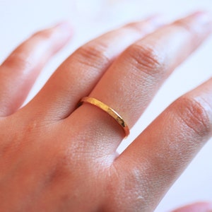 May include: A gold hammered ring on a finger.