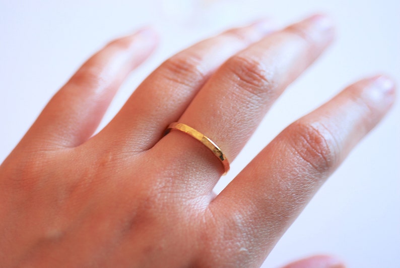 May include: A gold hammered ring on a finger.