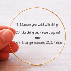May include: A gold bangle bracelet with instructions on how to measure your wrist for the perfect fit. The bangle measures 23.5 inches in circumference.