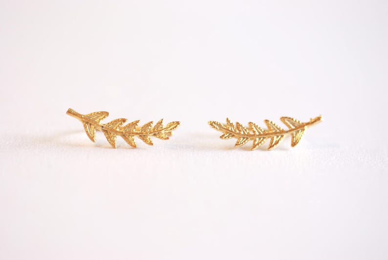 Pu&ograve; includere: Un paio di orecchini a forma di foglia d'oro. Gli orecchini sono a forma di felce e sono delicati e femminili.