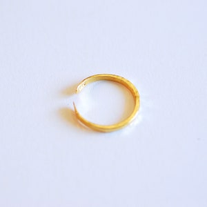 May include: A gold-colored ring with a simple, smooth design. The ring is open and appears to be made of metal.