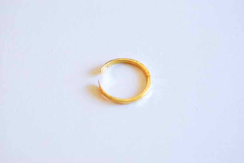 May include: A gold-colored ring with a simple, smooth design. The ring is open and appears to be made of metal.