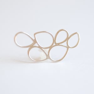 May include: Silver abstract earring with a cluster of interconnected oval shapes.