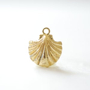 May include: A gold-colored seashell charm pendant with a loop at the top for attaching to a necklace or bracelet.