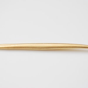 Könnte beinhalten: Ein goldfarbener Häkelhaken aus Metall mit einer spitzen Spitze.