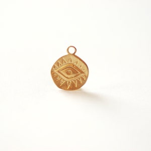 Puede incluir: Encanto dorado con un dise&ntilde;o detallado de ojo turco con un patr&oacute;n de rayos de sol alrededor. El encanto es redondo y tiene un bucle en la parte superior para sujetarlo a un collar o pulsera.