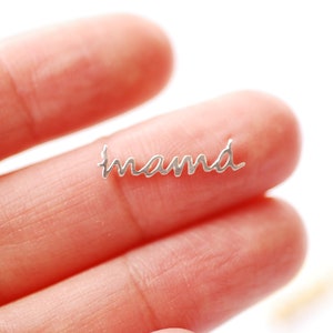 May include: A silver charm with the word "mama" written in cursive script.