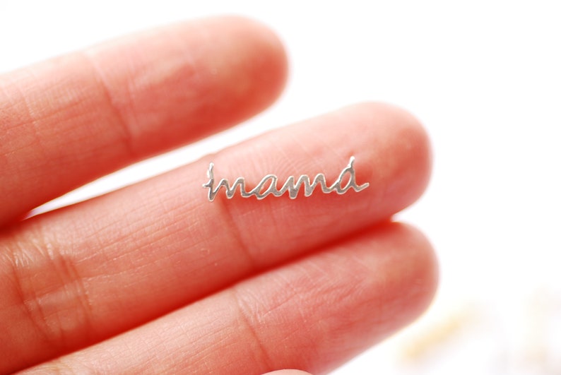 May include: A silver charm with the word "mama" written in cursive script.