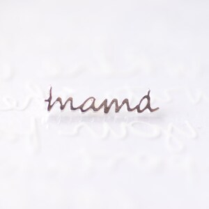 May include: Silver charm with the word "mama" written in cursive.