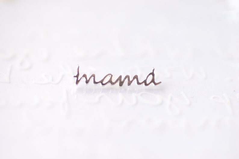 May include: Silver charm with the word "mama" written in cursive.