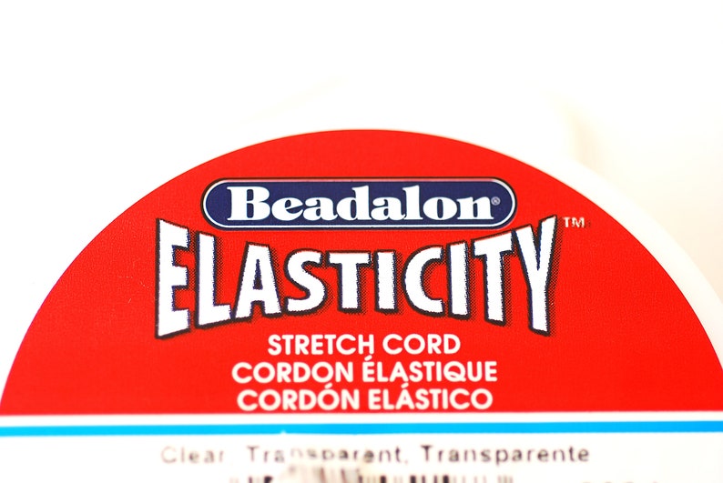 May include: A red and blue label with the text "Beadalon Elasticity Stretch Cord Cordon &eacute;lastique Cord&oacute;n el&aacute;stico Clear Transparent Transparente" on it.