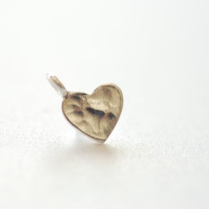 May include: A silver heart-shaped charm with a textured surface.