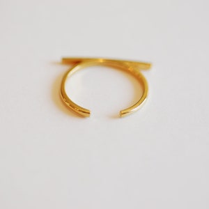 May include: A gold-colored ring with a horizontal bar across the top.