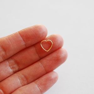 Puede incluir: Un peque&ntilde;o amuleto de coraz&oacute;n de oro, sostenido en una mano.