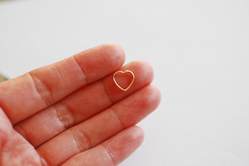Puede incluir: Un peque&ntilde;o amuleto de coraz&oacute;n de oro, sostenido en una mano.
