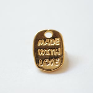 May include: Gold-coloured metal tag with the words "MADE WITH LOVE" embossed on it.