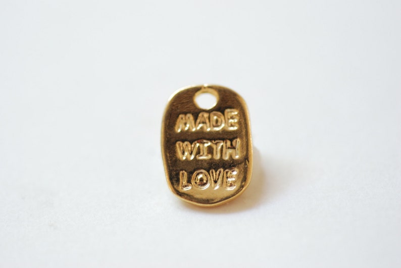 May include: Gold-coloured metal tag with the words "MADE WITH LOVE" embossed on it.