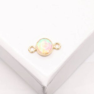 May include: Gold connector with a round opal-like stone in the center. The connector has two loops on either side.