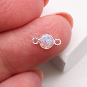 May include: A silver connector with a round, iridescent opal-like stone in the center. The connector has two loops on either side of the stone.