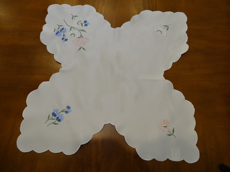 May include: White scalloped edge table runner with embroidered blue and pink flowers.