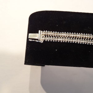 May include: Silver bracelet with a multi-strand chain design. The bracelet has a clasp closure.