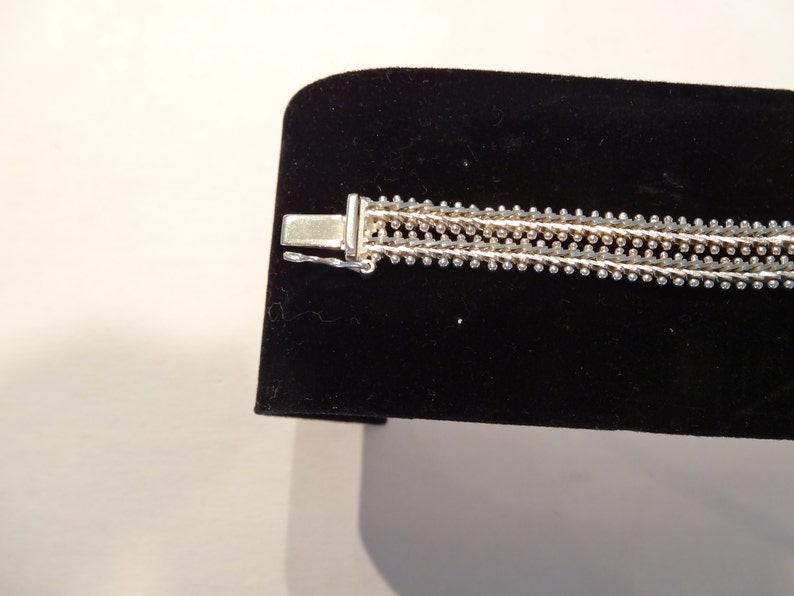 May include: Silver bracelet with a multi-strand chain design. The bracelet has a clasp closure.
