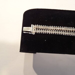 May include: A silver bracelet with a multi-strand design. The bracelet has a clasp closure.