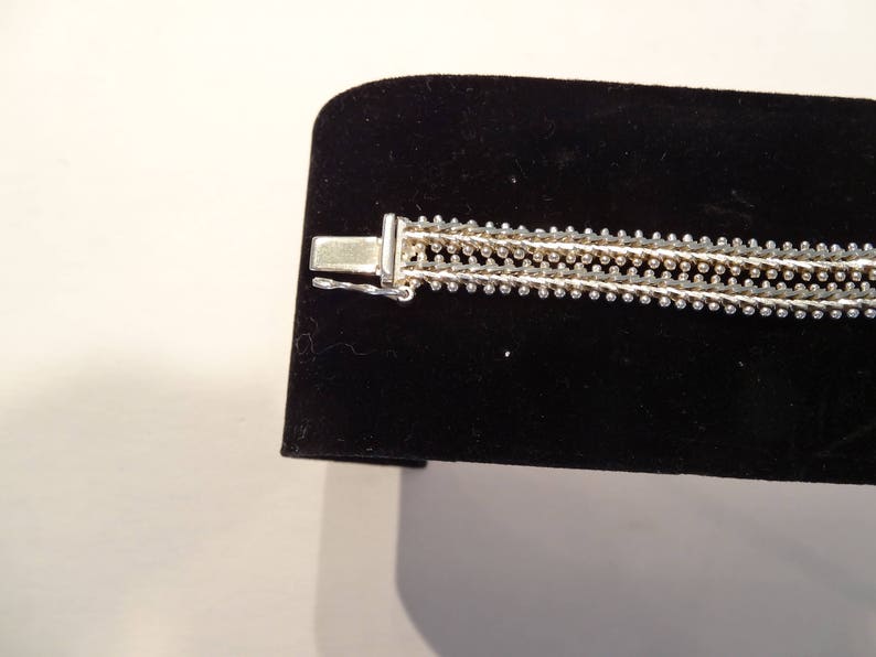 May include: A silver bracelet with a multi-strand design. The bracelet has a clasp closure.