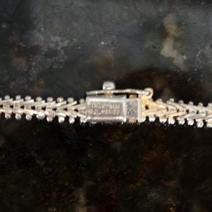 May include: Close-up of a silver chain with a clasp that reads "STERLING 925 ITALY MEXICO".