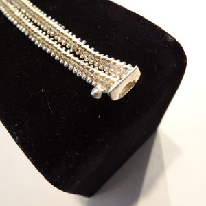 May include: A silver chain necklace with a delicate, layered design. The chain is made of small, round beads that are connected in a repeating pattern.