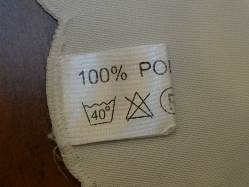 May include: White fabric label with black text that reads "100% POLY" and a washing instruction icon that says "40&deg;".