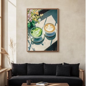 May include: A framed painting of two cups of coffee on a table. One cup is green and the other is brown with latte art. The cups are on a white table with a vase of flowers in the background.