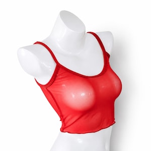 May include: A bright red sleeveless crop top made of a sheer, semi-transparent mesh fabric. The garment features a rounded scoop neckline and matching red trim along the armholes and collar, ending in a straight hemline at the midriff.