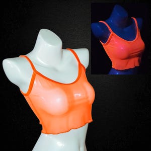 May include: Orange sheer crop top with thin straps and a ruffled hem. The top is displayed on a white mannequin, with a smaller image of the top on a blue mannequin in the background. The fabric appears to be lightweight and semi-transparent.