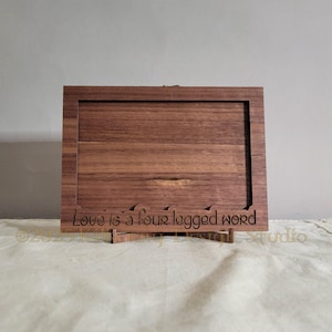 Puede incluir: Un marco de fotos de madera con un soporte, hecho de madera de nogal. El marco tiene un diseño recortado con el texto "Love is a four legged word".