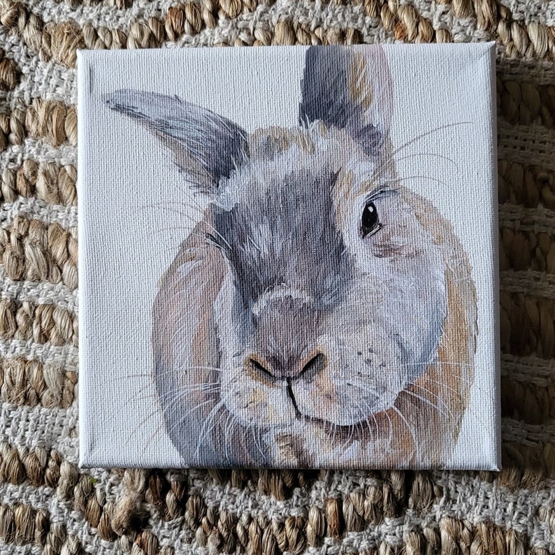 May include: A painting of a brown and gray rabbit with a white background. The rabbit has a fluffy coat and is looking directly at the viewer.