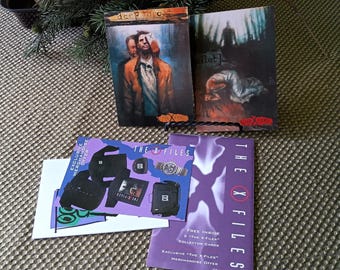 May include: Several X-Files themed items are displayed, including two small art prints and promotional cards. The prints feature artwork with the text "deep throat" and "pilot". The promotional cards are purple and white, with the text "The X Files".