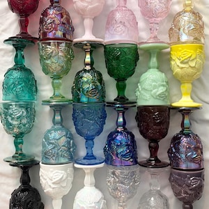 May include: A collection of twenty-five glass goblets arranged in a five-by-five grid. Each goblet features a raised floral pattern on the bowl and stem, with a variety of colors including red, green, blue, yellow, pink, black, and iridescent finishes.