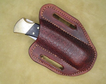Peut inclure: Un étui à couteau en cuir marron avec un bord cousu et un seul couteau à l'intérieur.