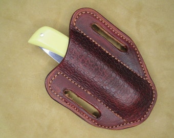 May include: A brown leather knife sheath with a stitched edge and a single knife inside.